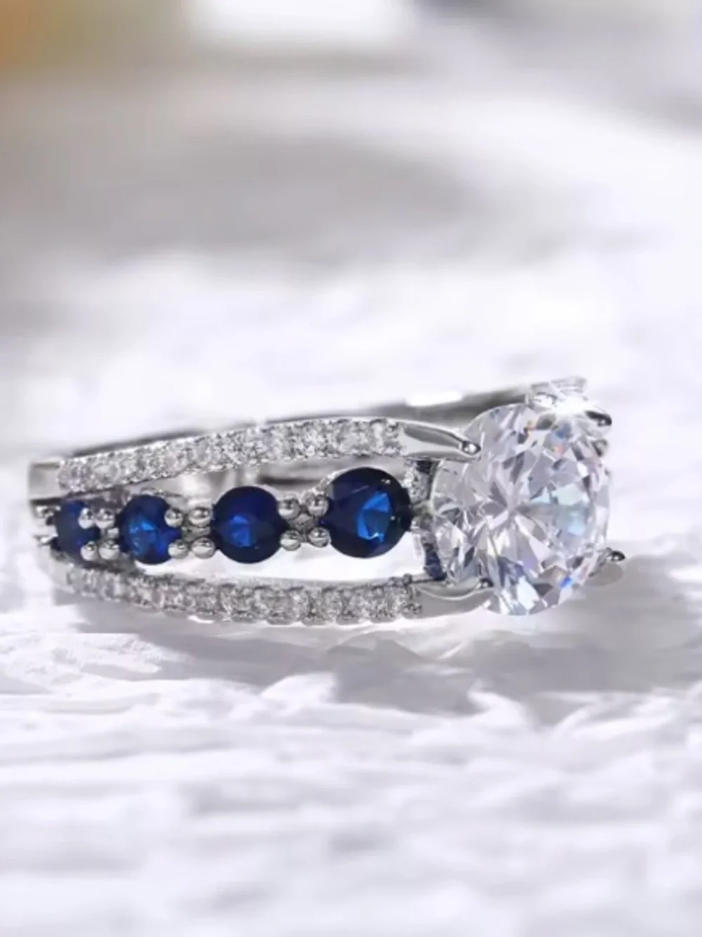 Silver Ring with Deep Blue Stones and Clear Center Gem.